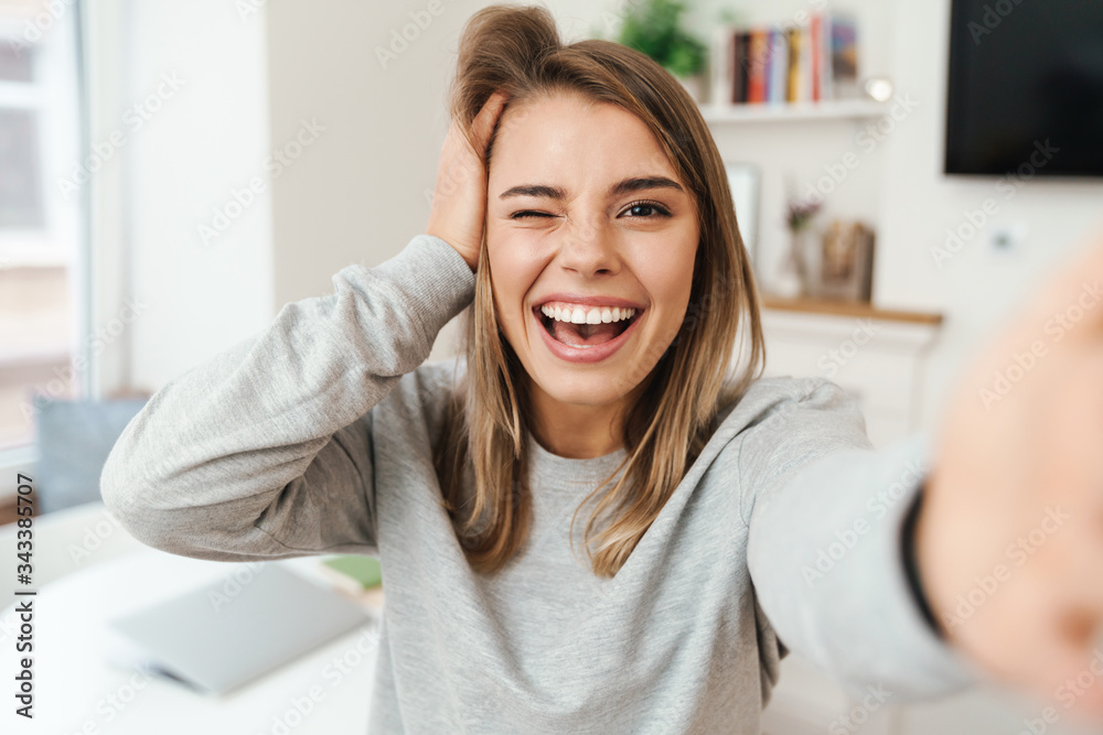Photo of cheerful woman laughing and winking while taking selfie photo Photo of cheerful woman laughing and winking while taking selfie photo