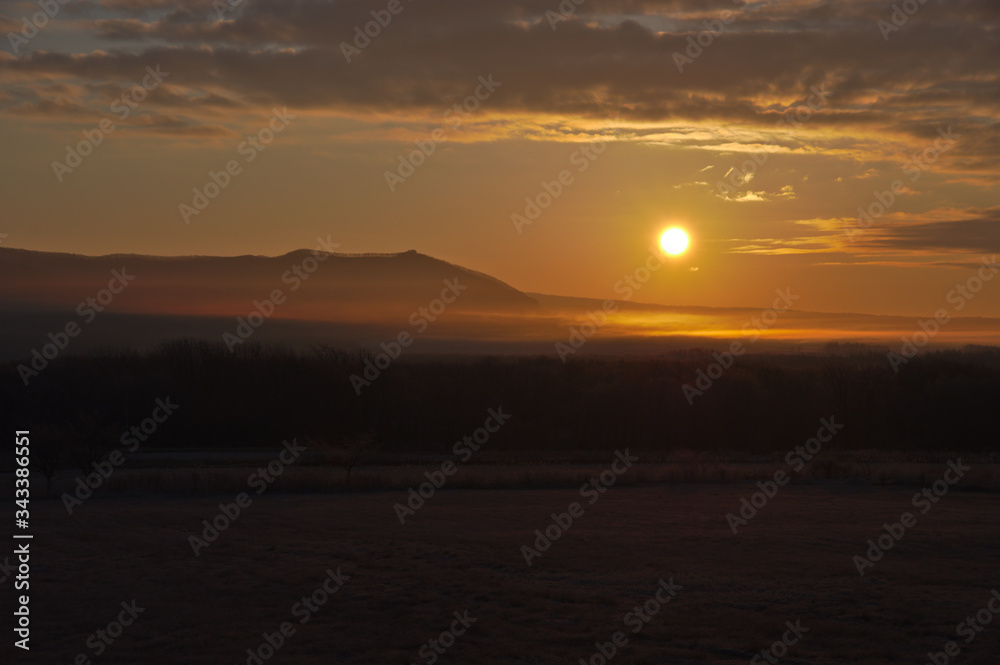 朝の太陽に弱く光る早暁の原野。北海道、日本。
