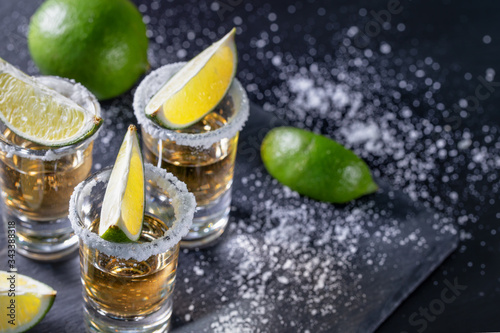 Tequila with lime on dark table with sprinkled salt