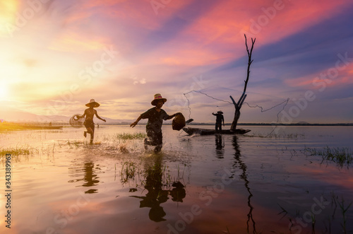 Silhouette of Thailand fisherman on wooden boat .