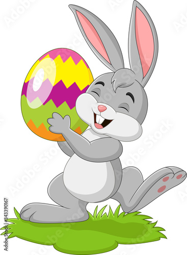 Cartoon little rabbit holding easter egg in the grass