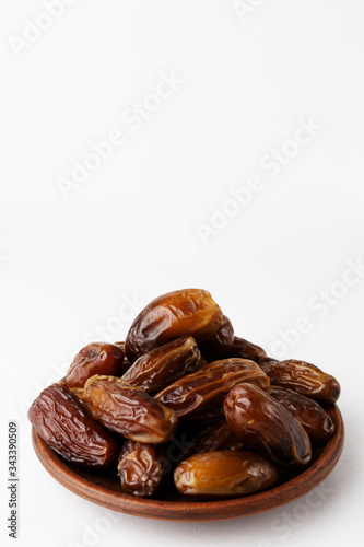 Dates on a clay plate on a white background. Vertical orientation