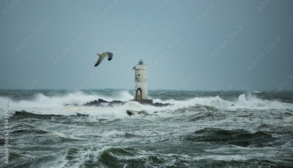 The lighthouse of the boat-eater shrouded by the waves of a mistral wind storm