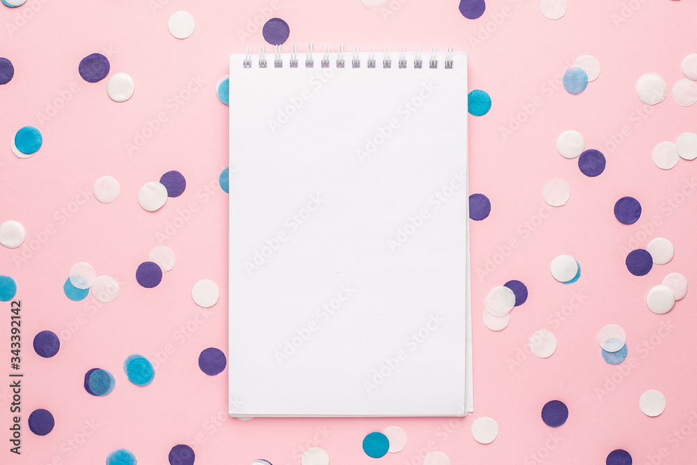 Notebook and blue, white and lilac confetti on pink color paper background minimal style Notebook and blue, white and lilac confetti on pink color paper background minimal style