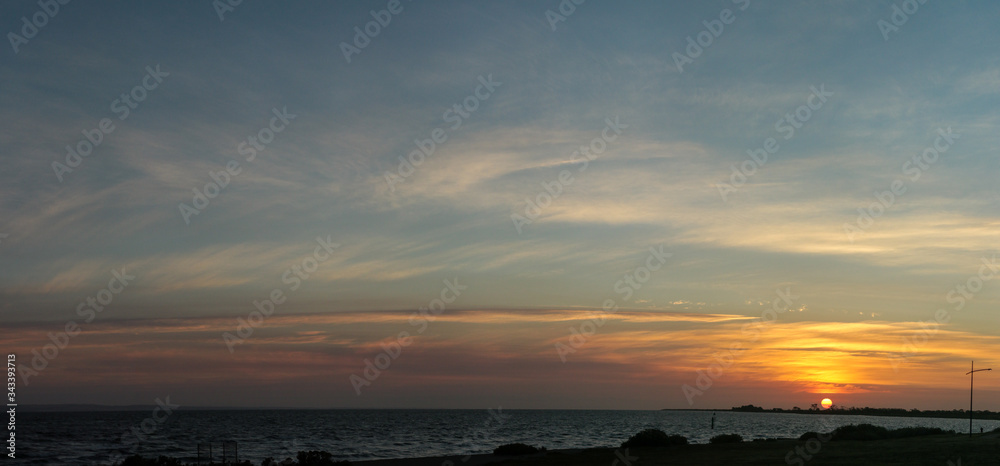 Panorama of the sun setting over a beach coastal scene along the bay near Melbourne, Victoria, Australia