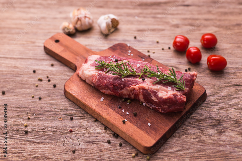 Raw beef fillet steaks with herbs and spices on wooden background