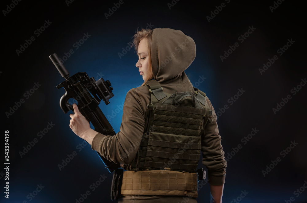 Fototapeta premium the girl in military overalls airsoft posing with a gun in his hands on a dark background