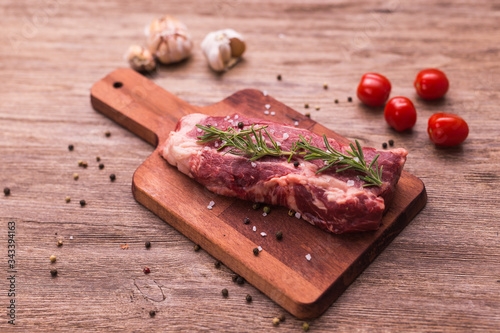 Raw beef fillet steaks with herbs and spices on wooden background