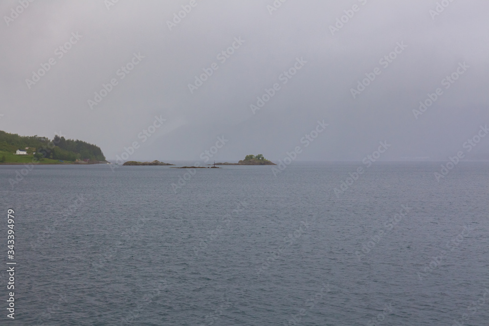Norwegian fjord and mountains surrounded by clouds, ideal fjord reflection in clear water. selective focus. Norwegian fjord and mountains surrounded by clouds, ideal fjord reflection in clear water. selective focus.