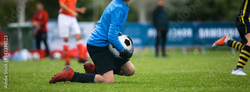 Young Football Goalkeeper Catching Soccer Ball. Soccer Goalie in Gloves on Knees During Sports Cometition Match