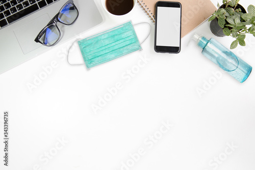 work from home work space office desk table top header layout on top have laptop , coffee cup, notebook, glasses, plant, smart phone modern style on white table in company at home in virus covid-19