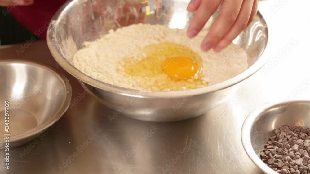 Woman mixing ingredients to prepare cookies at home - hands mixing eggs with flour - young woman making the mixture with her hands Woman mixing ingredients to prepare cookies at home - hands mixing eggs with flour - young woman making the mixture with her hands