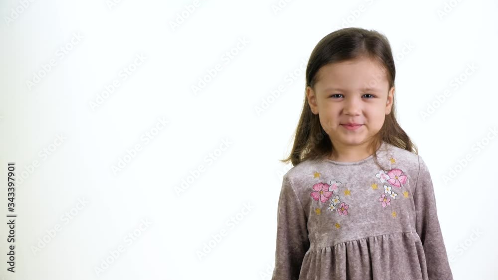 Cute little funny girl looking at camera and waving her hand on a white background. Childhood concept. Cute little funny girl looking at camera and waving her hand on a white background. Childhood concept.