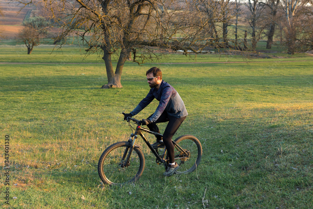 Cyclist in shorts and jersey on a modern carbon hardtail bike with an air suspension fork standing on a cliff against the background of fresh green spring forest Cyclist in shorts and jersey on a modern carbon hardtail bike with an air suspension fork standing on a cliff against the background of fresh green spring forest