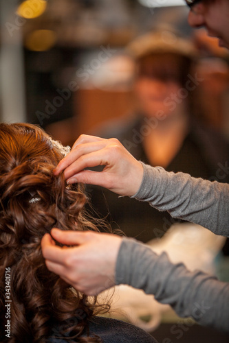 Hairdresser doing a woman's hair in professional hairdressing salon or barbershop , seen from behind the customer, unrecognizable.