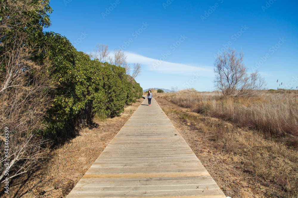 Woman walking on long wooden boardwalk trail