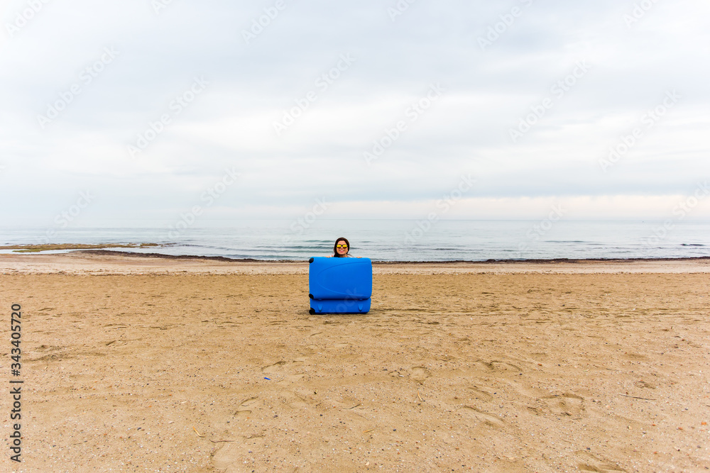 Woman with blue suitcase on the beach. Funny picture, joke and humor concept. Woman with blue suitcase on the beach. Funny picture, joke and humor concept.
