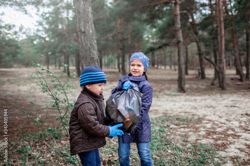 Kids with their father cleaning area in forest near beach, save the planet concept