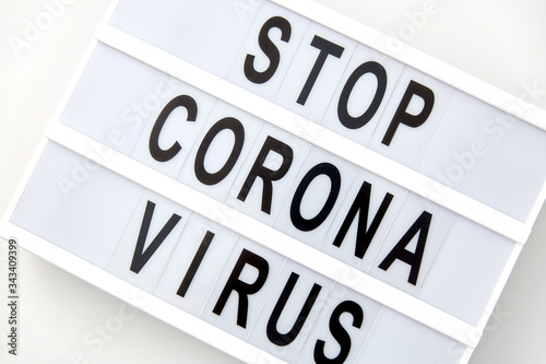 medicine, epidemic and healthcare concept - close up of lightbox with stop corona virus caution words on white background