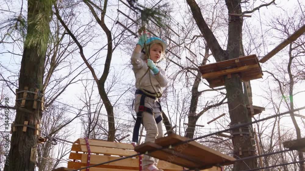 a child girl fears climb in rope Park in spring a child girl fears climb in rope Park in spring