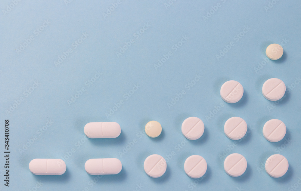 Flat layout white pills arranged in a row isolated on a blue background.copyspace for text.