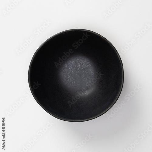 Empty blank black ceramic round bowl isolated on white background with shadow, Flat lay of traditional handcrafted kitchenware concept