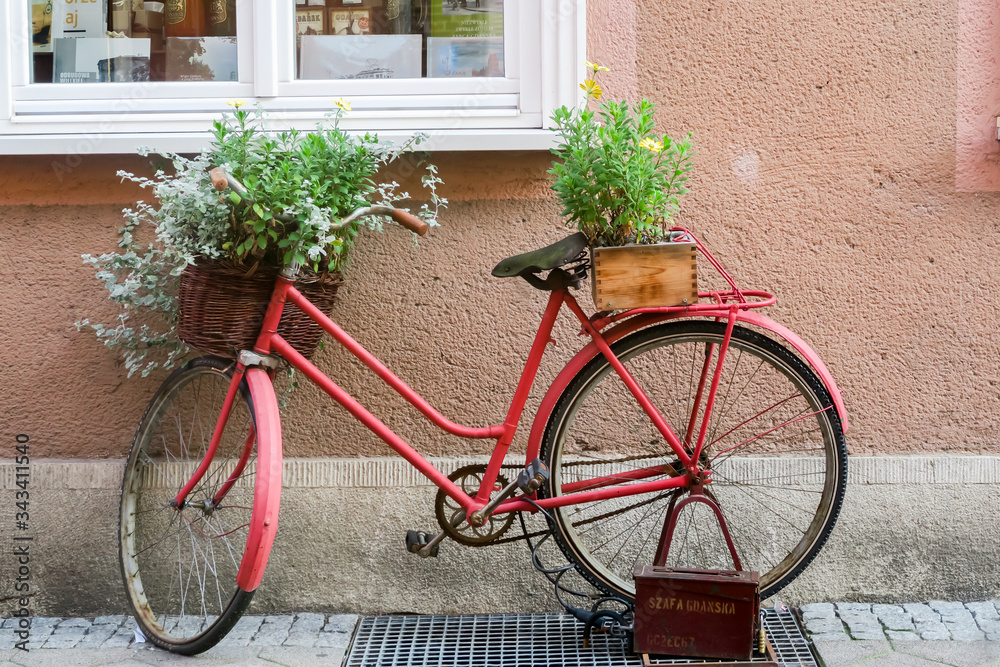 GDANSK, POLEN - 2016 SEPTEMBER 14. An old stylized red bike with baskets full of flowers standing on the street.