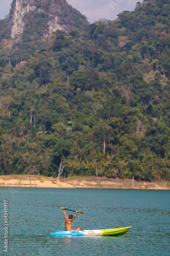 Young man kayaking on Cheo Lan lake in Khao Sok National Park. Thailand.