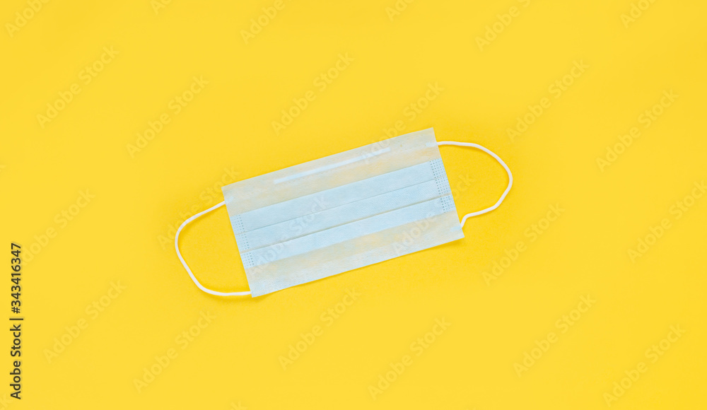 Medical mask on the yellow background, top view. Surgical masks flat lay. Coronavirus protection. Stop Covid-19. Hygiene and healthcare theme. Medical mask on the yellow background, top view. Surgical masks flat lay. Coronavirus protection. Stop Covid-19. Hygiene and healthcare theme.