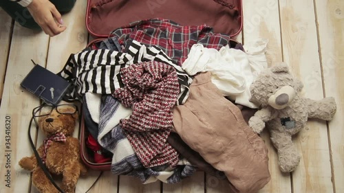 Faceless traveler woman trying to pack clothes in full owerflowing overfilled luggage. Mess nad disorder concept. Preparing for travel. Girl packing crammed suitcase. Tourism, journey lifestyle. photo