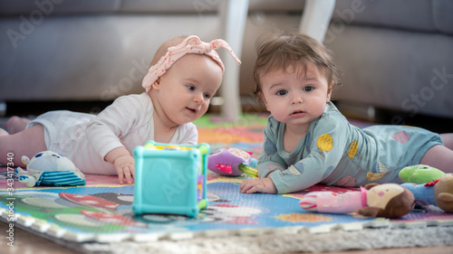 cute twins, baby girl and baby boy playing with toys by the home