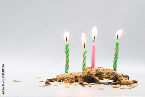 four birthday candle flame on mix nut and raisin cookies white background.