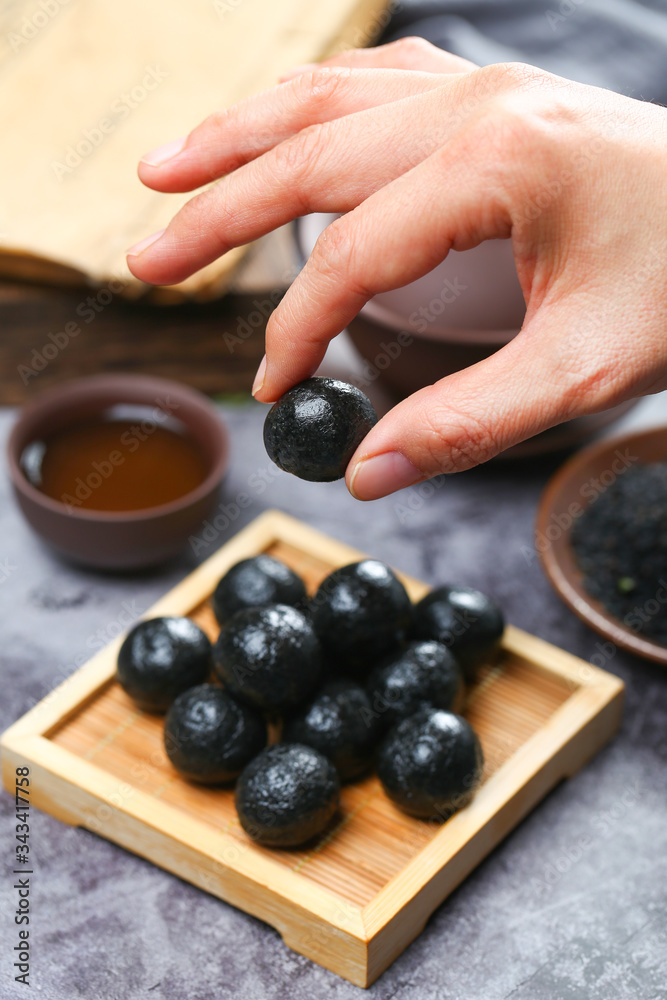 woman hand holing black sesame ball on bamboo plate with tea woman hand holing black sesame ball on bamboo plate with tea