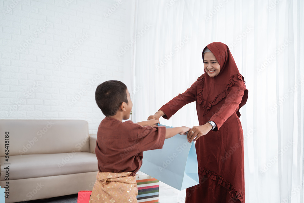 asian mother give gifts to their son using paper bag when Eid Mubarak