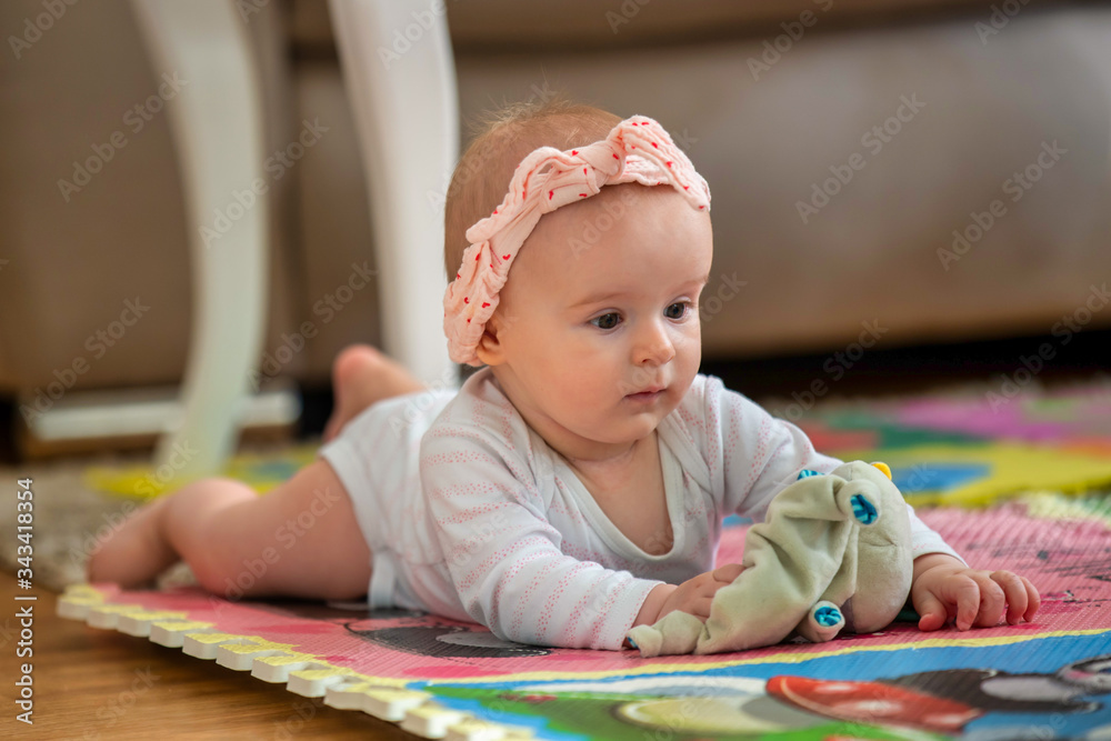 A cute young baby playing inside home with colorful toys A cute young baby playing inside home with colorful toys