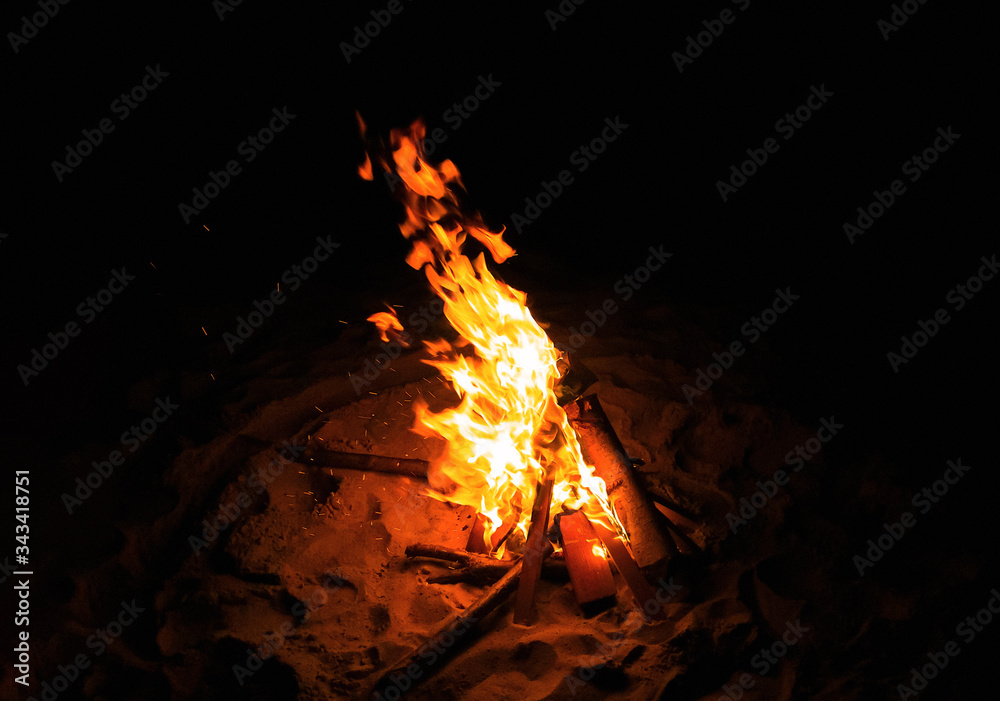 Magnificent bonfire at the sand beach in summer night. Dynamic flame in the wind. Campfire isolated on black background. Magnificent bonfire at the sand beach in summer night. Dynamic flame in the wind. Campfire isolated on black background.