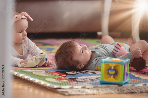 cute twins, baby girl and baby boy playing with toys by the home