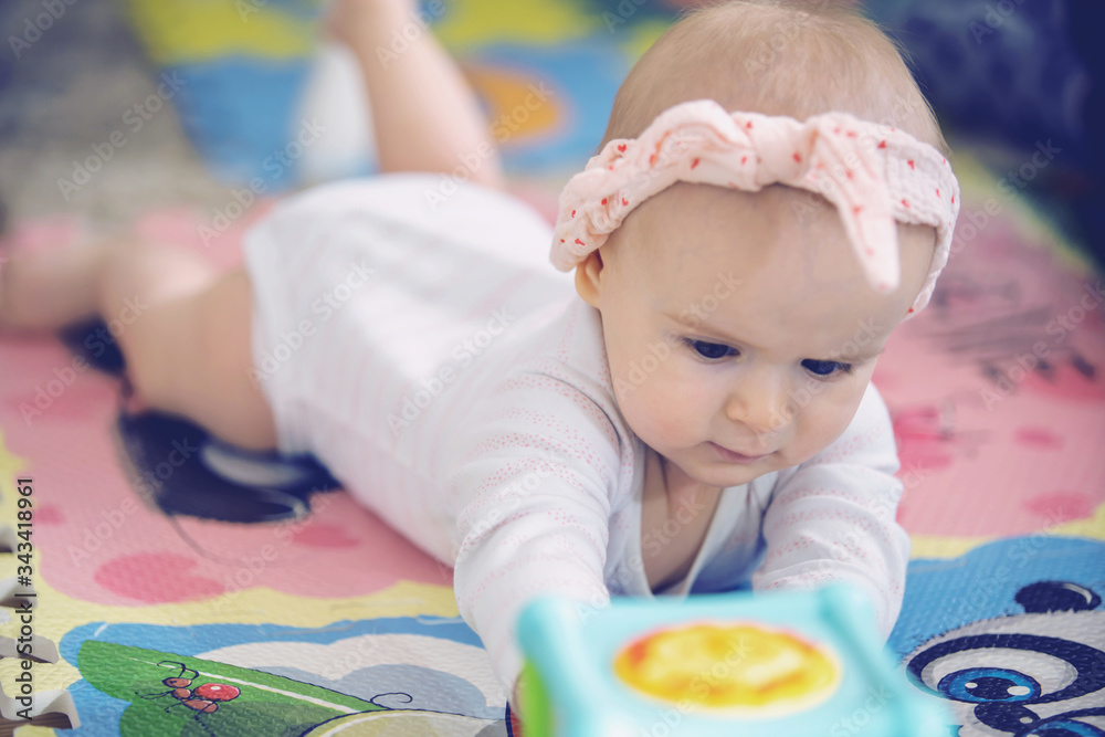 A cute young baby playing inside home with colorful toys A cute young baby playing inside home with colorful toys
