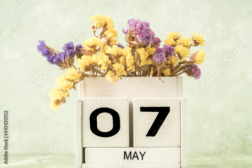 cube calendar for may decorated with flowers over green background with copy space