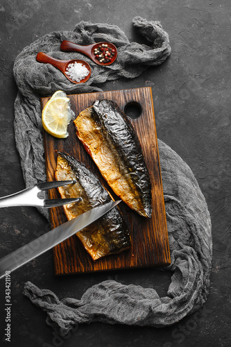 Delicious baked mackerel fillet with paprika, garlic and lemon, on a dark wooden Board with spices in the background. Top view, side view, close-up. Space for text.