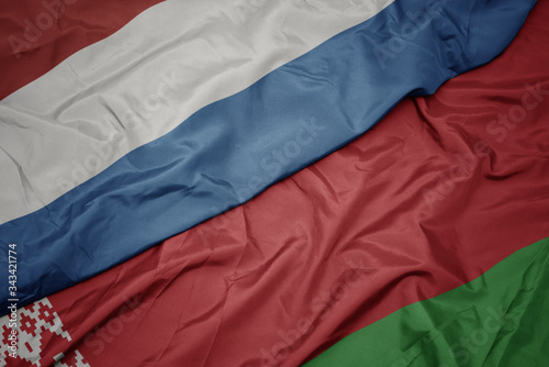 waving colorful flag of belarus and national flag of luxembourg.