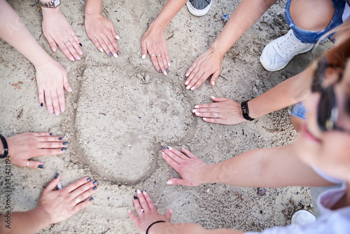 Close-up picture of women's hands on the sand. making the form of heart. Hen party celebration on the beach.
