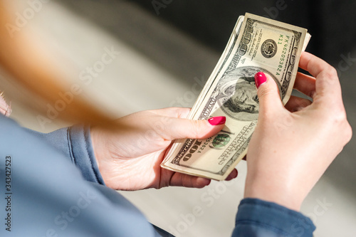 Close up on USD Dollar american money banknotes in hand of unknown caucasian woman holding currency after receiving payment loan or help financial aid support due to economic recession crisis top view