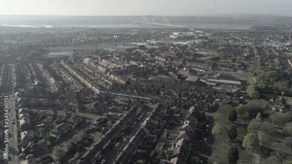 Aerial view flying above suburban British housing rooftops at sunrise golden hour dolly right