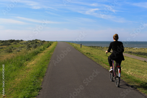 Fahrradfahrerin auf einem leeren Deichweg in Zeeland