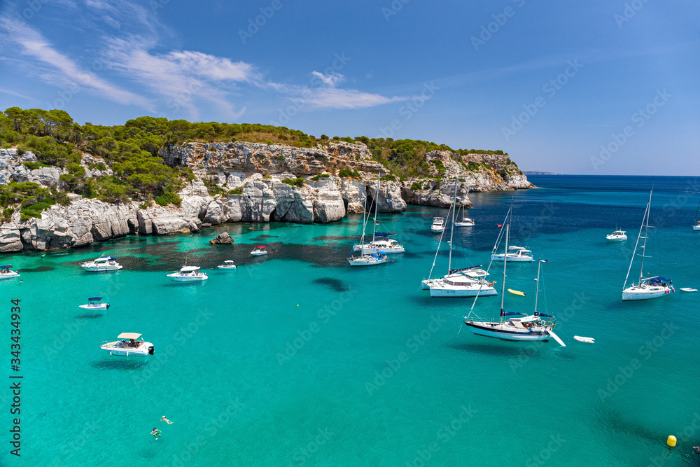 Panoramic view of the beautiful Macarella bay with many boats on the island of Menorca in Spain.