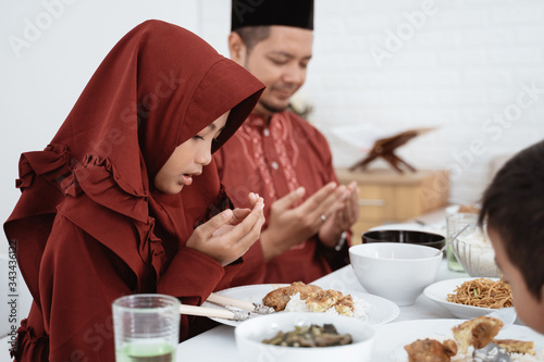Asian family sit and pray when breaking fast together at home