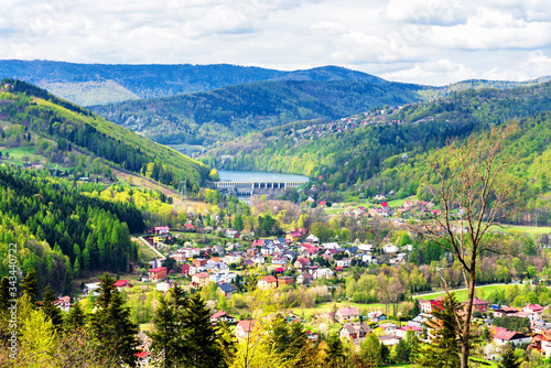 Fototapeta Naklejka Na Ścianę i Meble -  Aerial view of Miedzybrodzie town in Beskid Maly mountain range. Lake and dam in the background. Beautiful spring panorama.