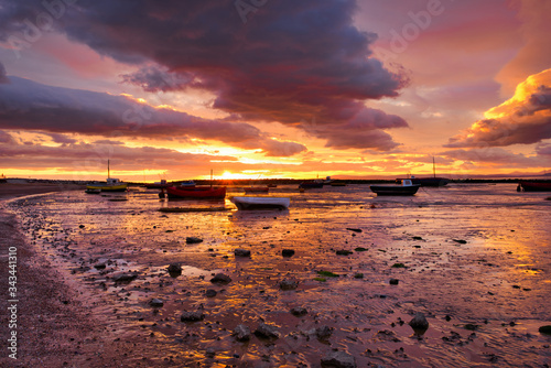 Sunset over beached fishing boats in Morecambe Bay, Lancashire, England. The estuary of Morecambe Bay is the largest area of intertidal mudflats and sand in the United Kingdom photo