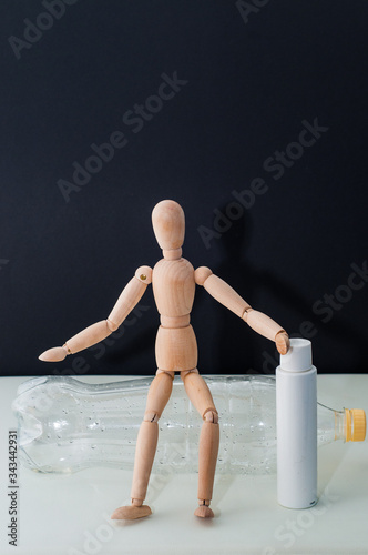 plastic bottle without water and wooden mannequin on black background